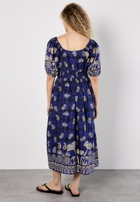 Maxikleid in Blau mit floralem Muster. Verfügt über Puffärmel, eine geraffte Taille und einen Saum mit einer dekorativen Bordüre.