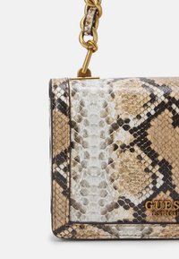 Borsa a tracolla con motivo in pelle di serpente in tonalità neutre, dotata di una tracolla in catena dorata e di un logo ben visibile. Superficie in pelle testurizzata.