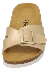 Beige slid sandal med en glansig lackfinish, ett brett rem med en guldtonad spänne och en texturerad korksula.