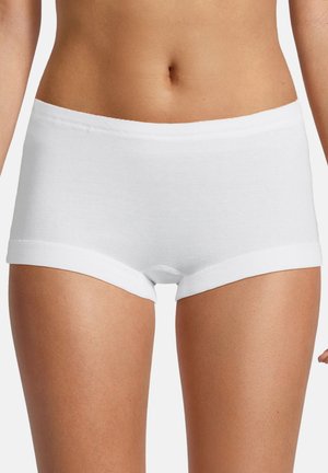 Frau trägt schlichte weiße Baumwoll-Boyshorts, zeigt Taille bis zur Mitte des Oberschenkels vor neutralem Hintergrund.