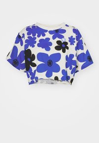Camiseta blanca corta con patrones de flores grandes en azul y negro y acentos de caras sonrientes, con mangas cortas y un escote redondo.