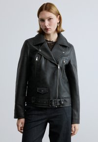 Schwarze Leder-Motorradjacke mit weitem Kragen, Reißverschlusstaschen und einem taillierten Gürtel. Verfügt über eine strukturierte Oberfläche und metallische Hardware-Akzente.