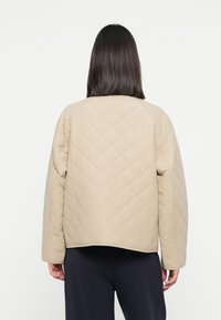 Beige, quilted jakke med avslappet passform, rund halslinje og lange ermer. Har diamantmønster og myk tekstur for komfort.