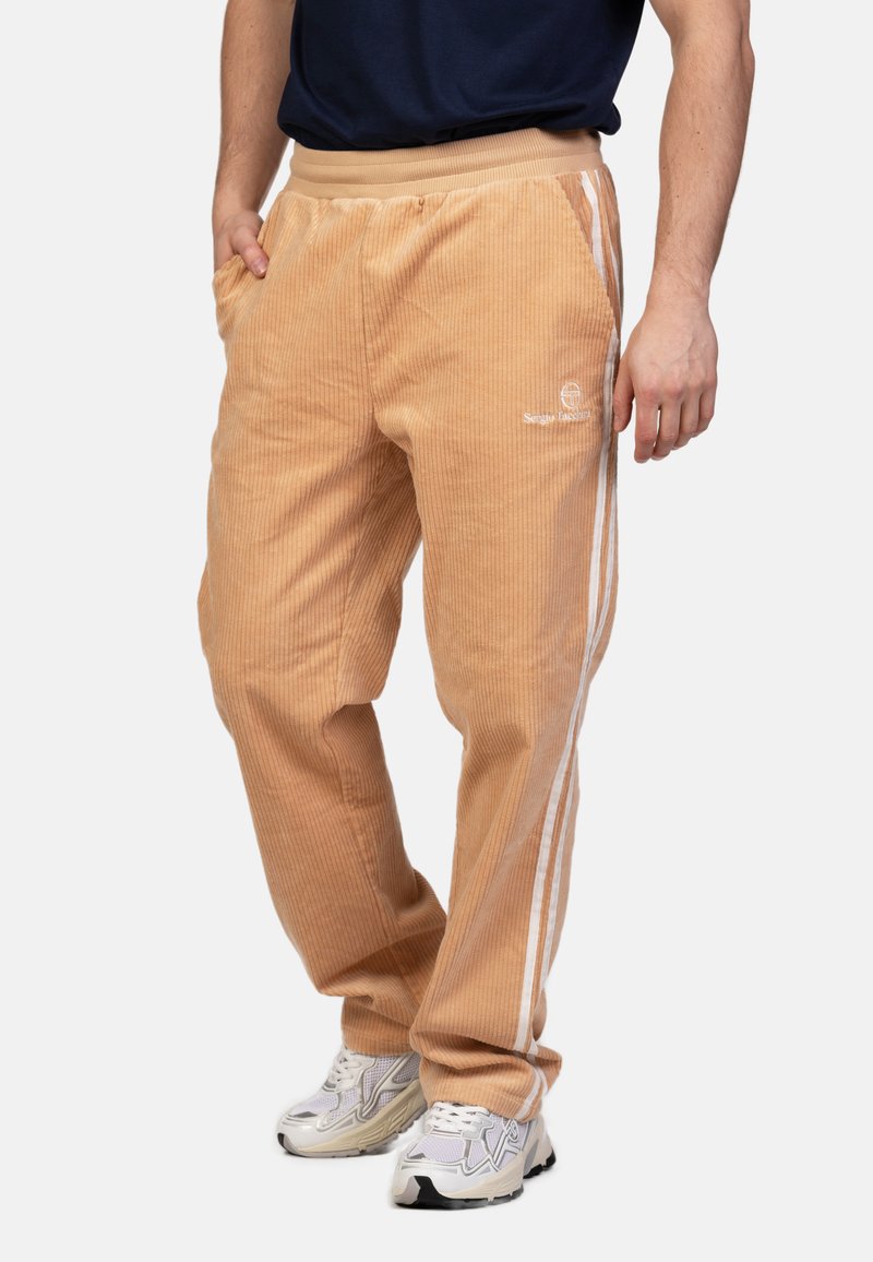 Beige corduroy bukser med en lodret ribbet tekstur, prydet med hvide sidelige striber og en elastisk talje. Forlommer inkluderet.
