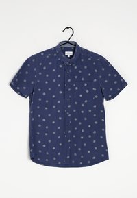 Chemise à manches courtes en tissu bleu marine avec des motifs circulaires gris, col boutonné et poche à gauche sur la poitrine. Texture lisse, design décontracté.