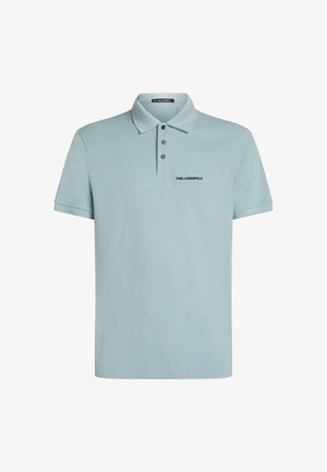 Svetlo modra polo majica iz teksturiranega materiala. Ima klasičen ovratnik, zapenjanje na tri gumbe in črn logotip izvezen na prsih.