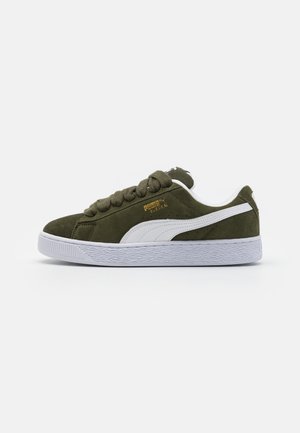 Baskets en nubuck vert olive avec accents blancs, bout rond et épaisse semelle en caoutchouc blanc. Présente une semelle extérieure texturée et des lacets plats.