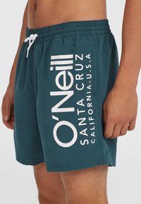 Shorts de bain teal avec un logo blanc affichant "O'Neill SANTA CRUZ CALIFORNIA U.S.A." sur le côté; taille élastique avec cordon de serrage.