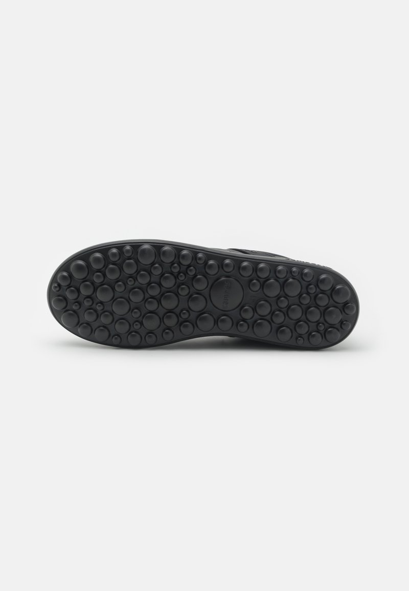 Black shoe sole featuring a textured surface with round bubble-like patterns, designed for traction and grip. Flat profile with no visible branding.