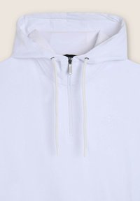 Felpa con cappuccio bianca con zip e coulisse, caratterizzata da una texture morbida e un logo ricamato discreto. Il design include un ampio cappuccio.