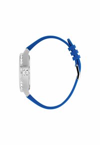 Ura z ročno obliko s pravokotno srebrno kovinsko ohišje, modrim silikonskim trakom in teksturirano obrobo. Ima kovinsko zaponko in vzorčasto dodatno podrobnost na traku.