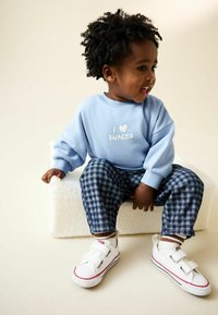 Sudadera azul claro con texto "I ❤️ SNACKS", pantalones a cuadros azul y blanco, y zapatillas blancas con detalles rojos y cierres de velcro.