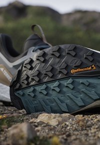 Close-up van een sneakerzool met een robuust profielpatroon op steenachtige ondergrond, met het Continental-merklogo op de zool.
