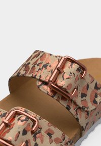 Πέδιλα με διπλές φαρδιές λουρίδες σε μπεζ και χαλκοκίτρινο λεοπάρ μοτίβο, κάθε λουρίδα διαθέτει αγκράφα από ροζχρυσαφί μέταλλο για ρύθμιση.