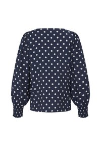 Blouse bleu marine à manches longues avec des pois blancs, manches bouffantes et poignets élastiqués froncés.