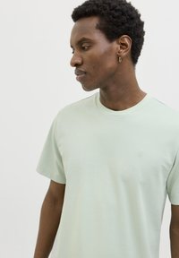 Lichtgroen katoenen T-shirt met korte mouwen, ronde hals en subtiel logodetail op de borst. Gladde textuur en rechte snit.