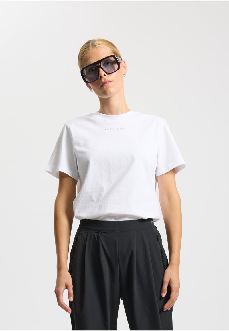 Hvid bomulds t-shirt med korte ærmer, dekoreret med et trykt logo. Kombineret med høj talje sorte bukser, der fremhæver en afslappet pasform.