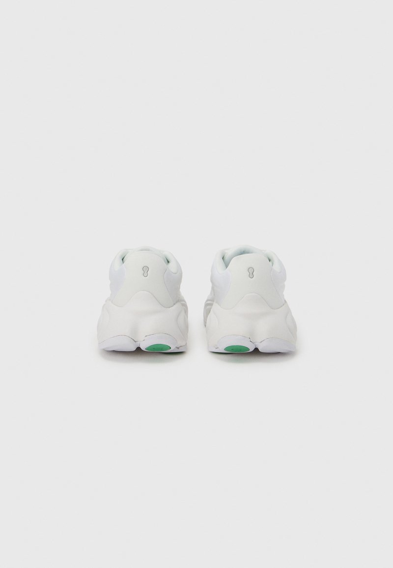 Witte sneakers met een afgeronde vorm, gewatteerde hiel, glad synthetisch bovenwerk en een groene accentkleur op de zool. Minimalistisch ontwerp.