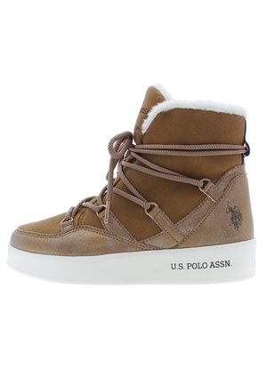 Stivale alla caviglia in suede marrone con foderatura in pelliccia sintetica bianca, punta rotonda e allacciatura frontale. Presenta una suola intermedia bianca con il logo "U.S. Polo Assn.".