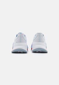 Zapatillas deportivas en azul y blanco con parte superior de malla texturizada, suela acolchada y acentos rojos en el talón. Presenta un diseño de parte trasera redondeada.