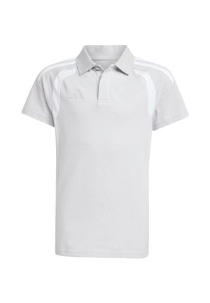 Junge mit kurzen Haaren, der ein weißes Adidas-Poloshirt und schwarze Hosen mit weißen Streifen vor schlichtem hellem Hintergrund trägt.