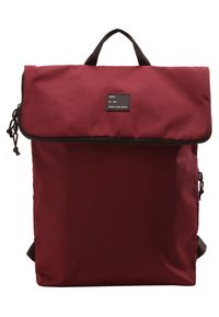 Mochila marrón con un diseño de roll-top, detalles en negro y un parche con el logo en la parte frontal. Fabricada con un tejido duradero y correas laterales ajustables.