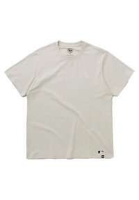 Camiseta de manga corta y cuello redondo en color beige claro, hecha de un tejido suave, con un pequeño logo blanco en el pecho y una etiqueta de color en el dobladillo.