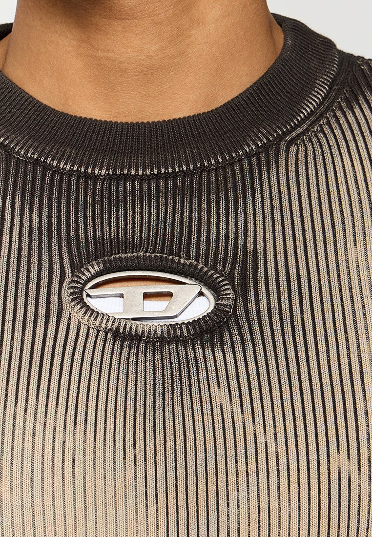 Strickpullover mit abwechselnden schwarzen und beigen vertikalen Streifen, versehen mit einem silbernen ovalen Logo-Akzent am Halsauschnitt.