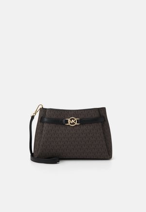 Petit sac-bracelet de créateur brun foncé avec sangle en cuir noir et fermoir logo MK doré sur le devant, sur fond blanc.