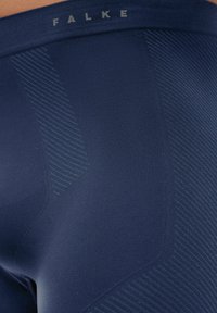 Navy blue activewear tights with a smooth texture and ribbed accents. Features the "FALKE" logo near the waistband.