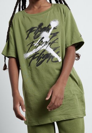 Kind trägt olivgrünes T-Shirt mit weißem und schwarzem Motiv eines springenden Basketballspielers und dem Wort "Flight", das dahinter wiederholt wird.