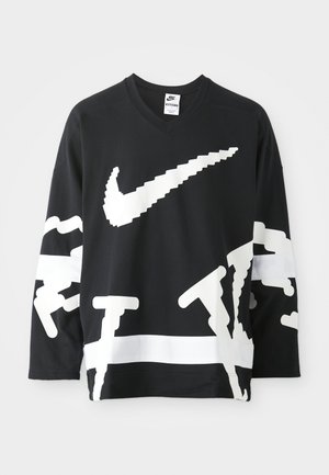 Musta pitkähihaan v-aukkoinen collegepaita, jossa on suuri valkoinen Nike-logo ja abstrakti graafinen kuvio. Paidassa on teksturoidusta kankaasta valmistettu rakenne ja kontrastivalkoinen paneeli.