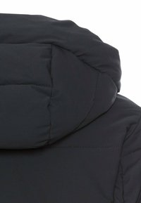 Mørk pufferjakke med hætte, der har et quiltet design med synlige sømme. Glat tekstur, der tilbyder isolering og varme.
