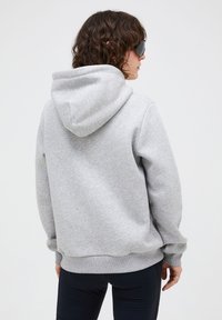 Graue Kapuzenjacke mit gerippten Bündchen und Saum. Weiche Textur, lockere Passform und ein schlichtes Design. Verfügt über eine große Kapuze auf der Rückseite.