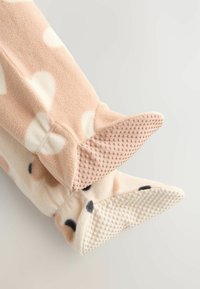 Fleecowe buciki w jasnoróżowym kolorze w białe kropki z antypoślizgowymi, teksturowanymi podeszwami w kontrastujących odcieniach różu i kremu. Miękka, przytulna tkanina.