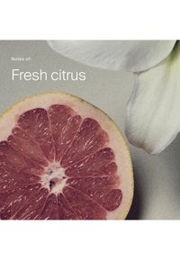 Eine halbe rote Grapefruit neben weißen Blumenblättern mit dem Text „Noten von: Frischer Zitrus“ auf grauem Hintergrund.