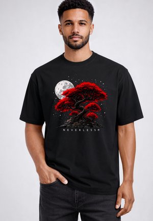 Man wearing black t-shirt featuring red bonsai tree, full moon, and stars with "NEVERLESS" text below design.