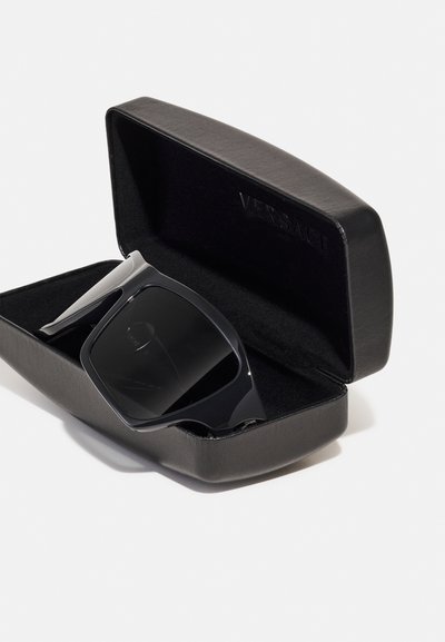 Black sunglasses with a bold design inside a black leather case. The frame is sleek, featuring a matte finish and dark lenses.