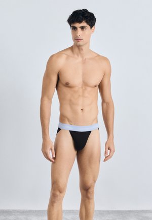 Črne tangice z elastičnim pasom svetlo modre barve, ki nosi logo "Calvin Klein". Preprost dizajn, gladka tekstura in minimalna prekrivnost.