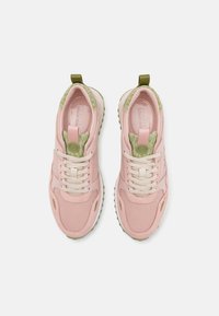 Gaiši rozā sporta apavi ar gludu auduma augšdaļu, beigu krāsas auklām, zaļu akcentu uz papēža un teksturētu apdari uz mēles.