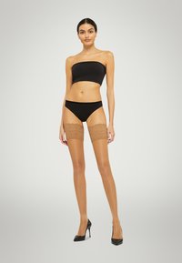 Schwarzes Bandeau-Top, schwarze Bikinihose, beigen Spitzenstrumpf mit hohen Schaft, hohe Absätze. Glatte Textur, tailliertes Design.