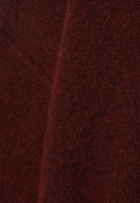 Tissu en laine bourgogne avec une surface douce et texturée, présentant une apparence légèrement chinée et une profondeur de couleur riche.