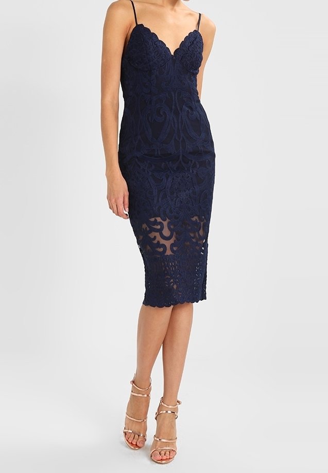 Robe en dentelle bleu marine avec des motifs floraux complexes, silhouette ajustée, décolleté en V et ourlet transparent. Bretelles spaghetti et détails élégants.
