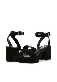 Sandali platform in suede nero con cinturini alla caviglia, punta aperta e fibbie color oro. Presentano un tacco spesso e una soletta nera liscia.