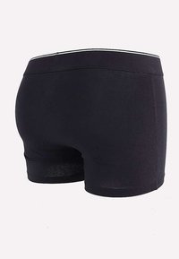 Boxer shorts en coton noir avec une texture lisse, dotés d'une ceinture contrastante blanche. Coupe courte et ajustée avec un design de couture exposée.