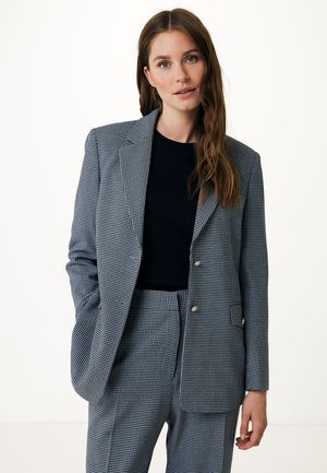 Blazer a scacchi in bianco e nero, con rever a punta, doppi bottoni e una vestibilità su misura, abbinato a una maglietta nera a girocollo.