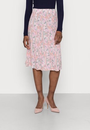 Jupe midi florale dans des tons de rose, rouge et vert. Tissu léger et fluide avec un ourlet froncé. Portée avec des escarpins rose pâle.