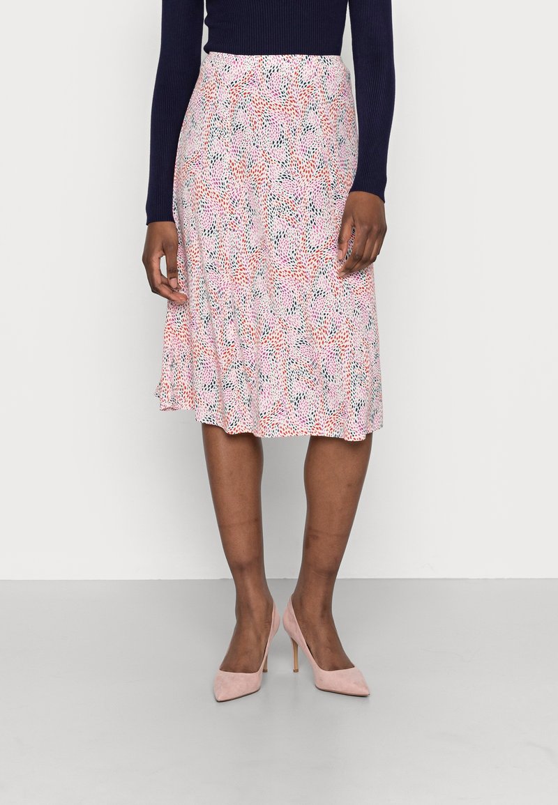 Blomster midi nederdel i nuancer af pink, rød og grøn. Let, svævende stof med en samlet kant. Båret med lyserøde højhælede sko.
