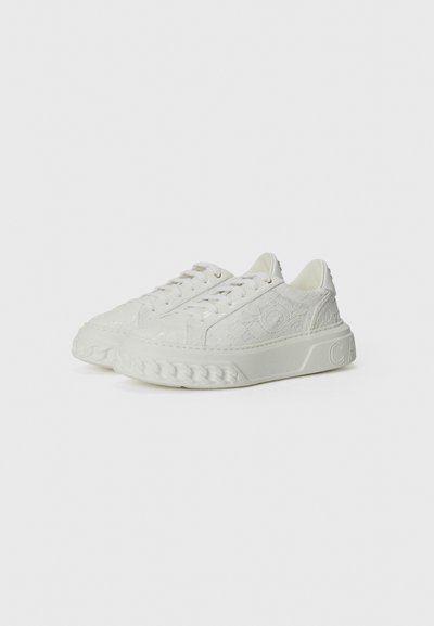 Vita sneakers med en präglad textur, utrustade med en tjock, flätad sula och diskret branding på sidan. Platta snören kompletterar designen.