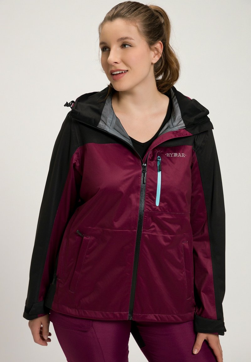 Vattentät jacka i vinröd med svarta accenter. Har en huva, framdragkedja och fickor. Tillverkad av ett slätt, lätt material.